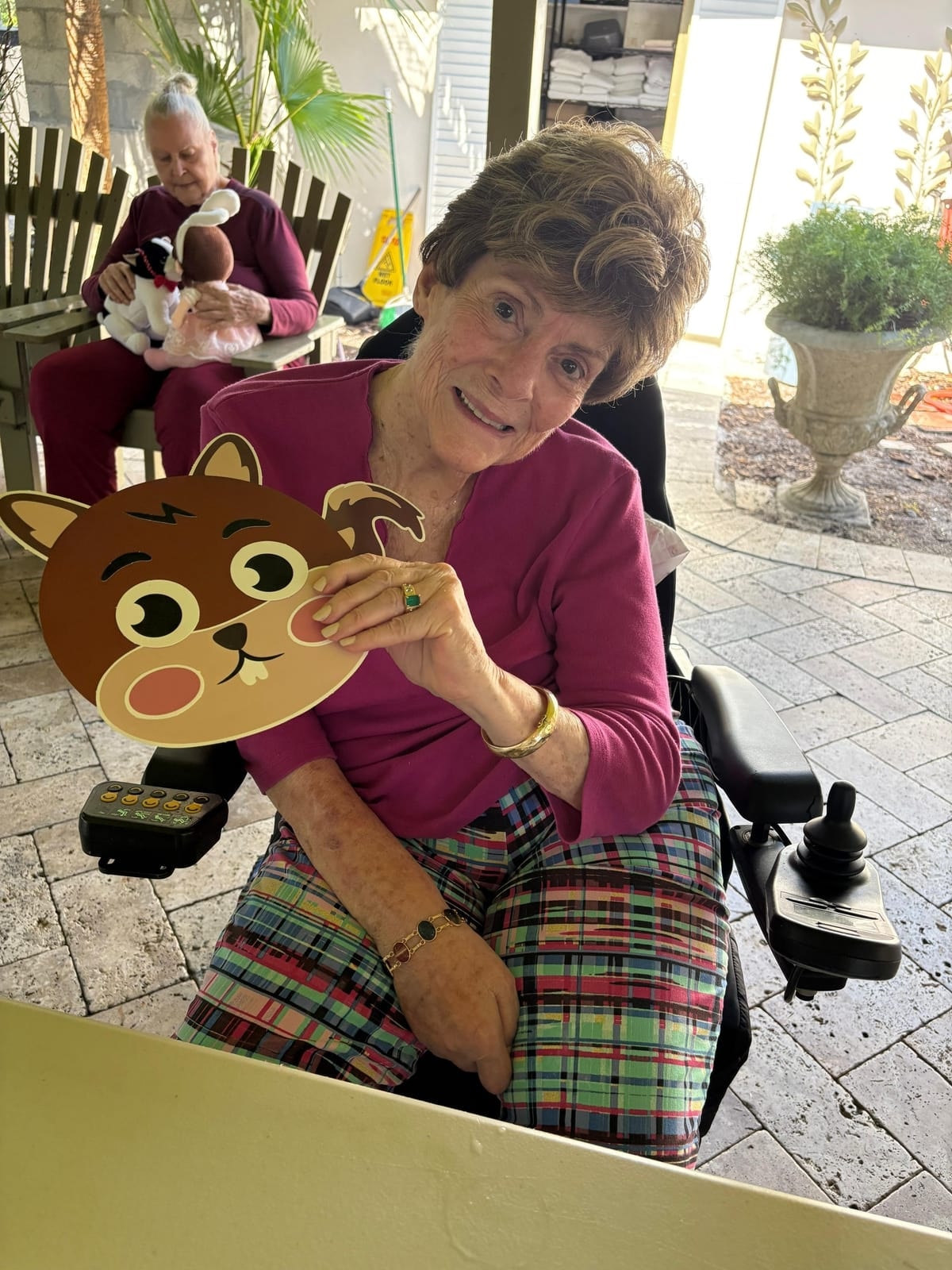 A smiling resident with a craft mask on the patio at Royal Palm Senior Residence.