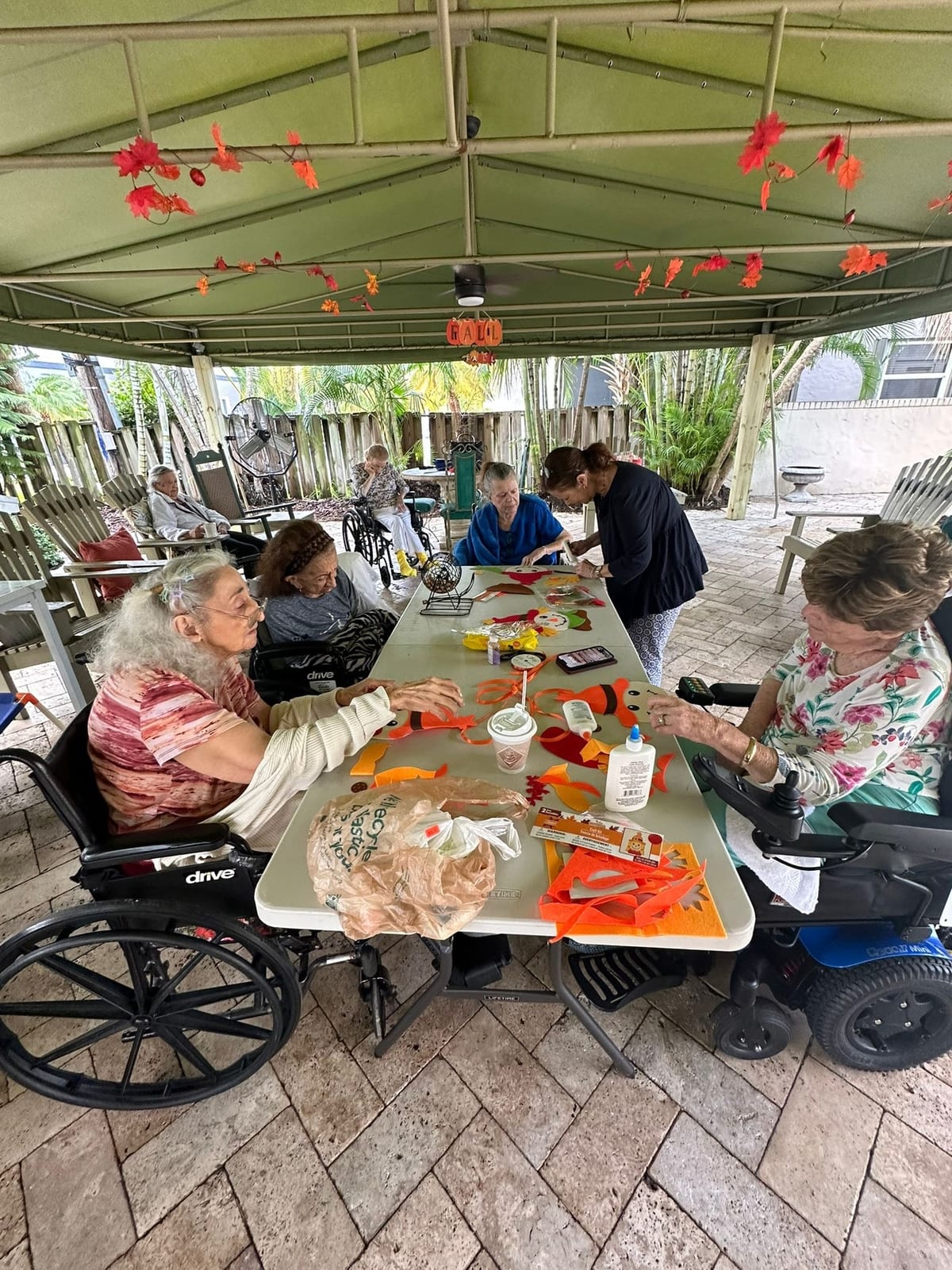 Residents at a craft table under the patio at Royal Palm Senior Residence.