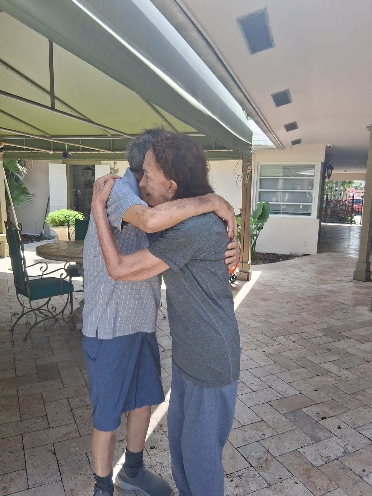 Two residents sharing a warm moment outdoors at Royal Palm Senior Residence.