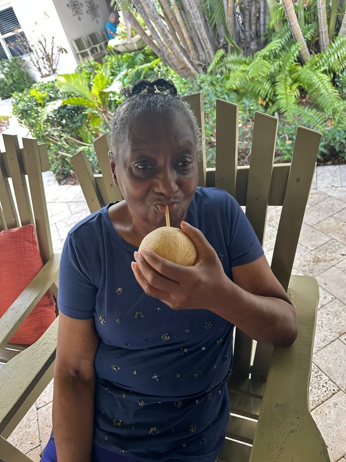 A resident enjoying a coconut drink on the patio at Royal Palm Senior Residence.