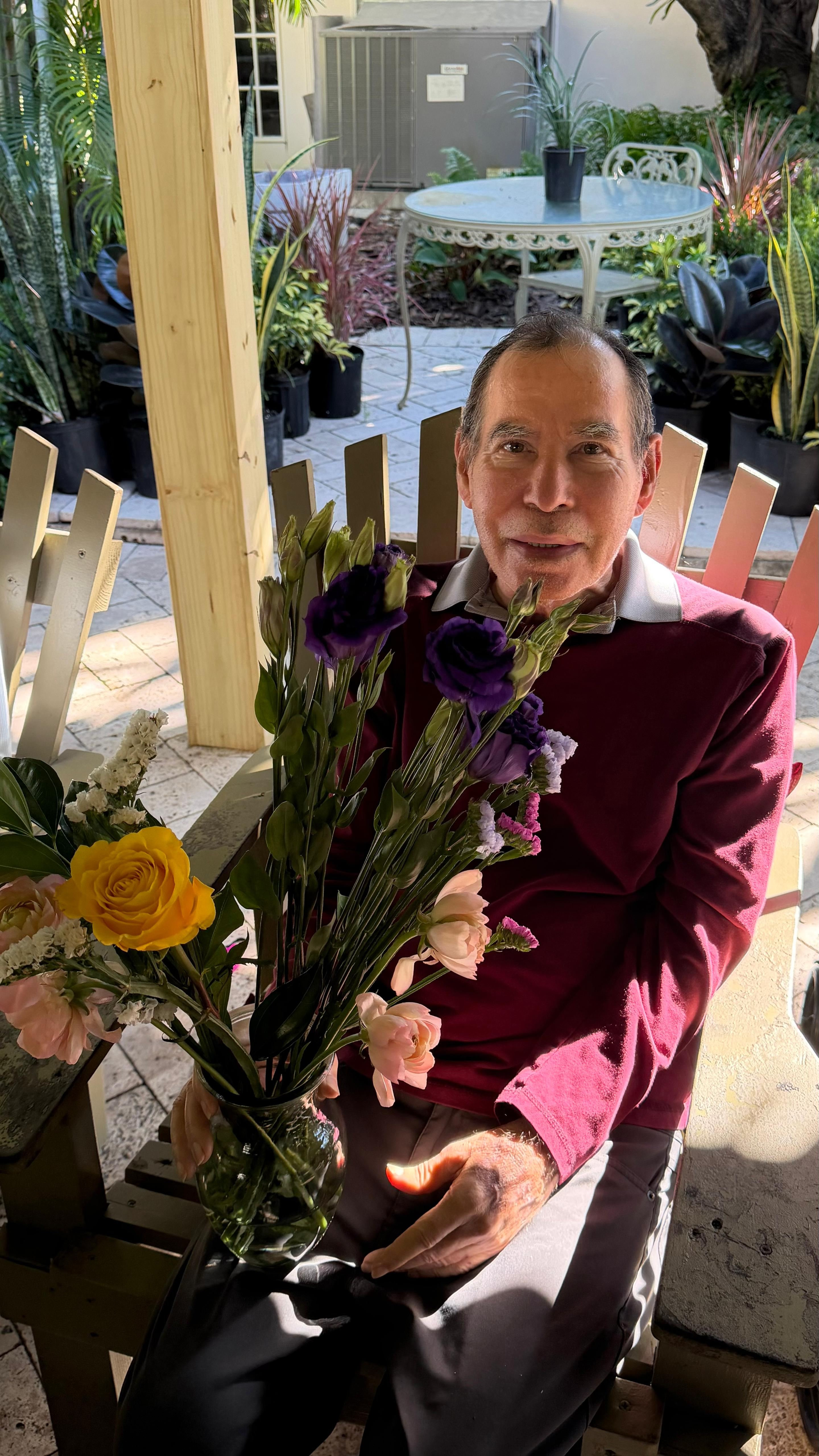A resident with flowers on the patio at Royal Palm Senior Residence.