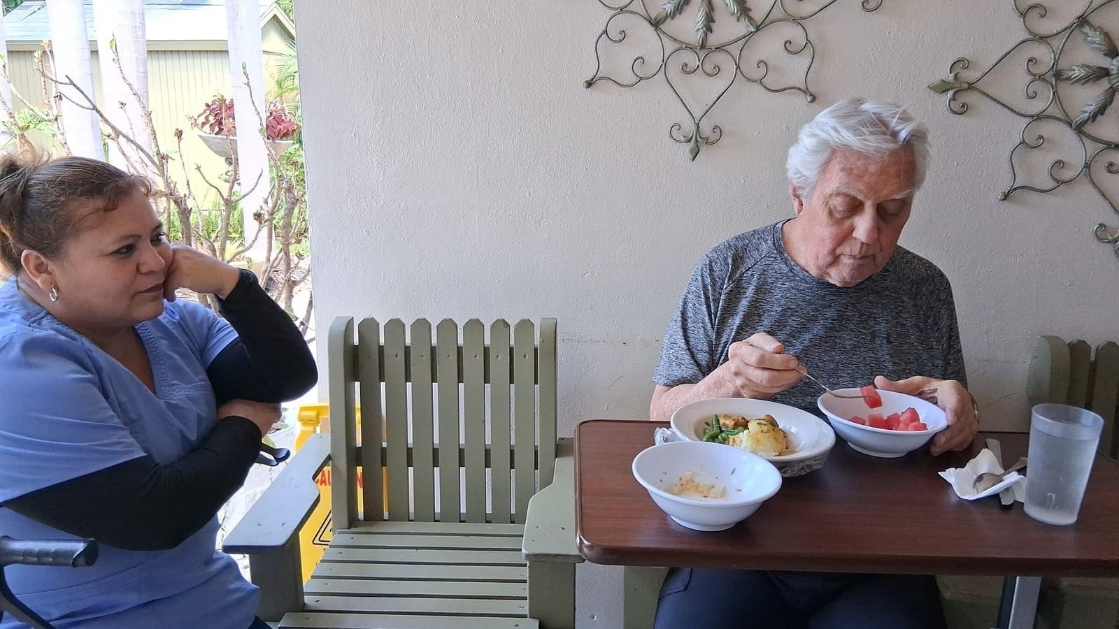 A resident enjoying a meal with staff nearby at Royal Palm Senior Residence.