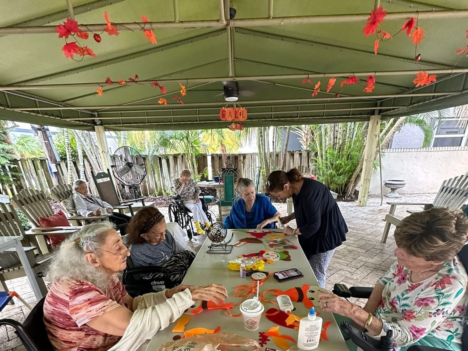 Residents at a craft table under the patio at Royal Palm Senior Residence.