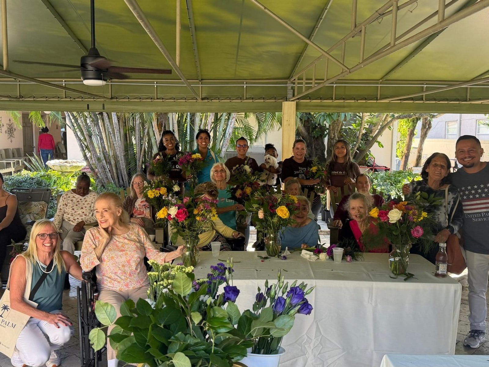 Residents and staff arranging flowers under the patio at Royal Palm Senior Residence.