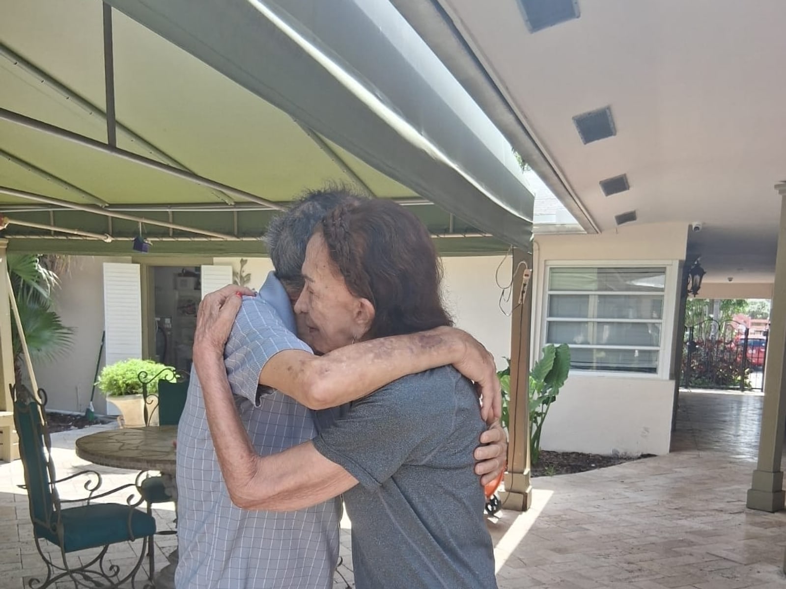 Two residents sharing a warm moment outdoors at Royal Palm Senior Residence.